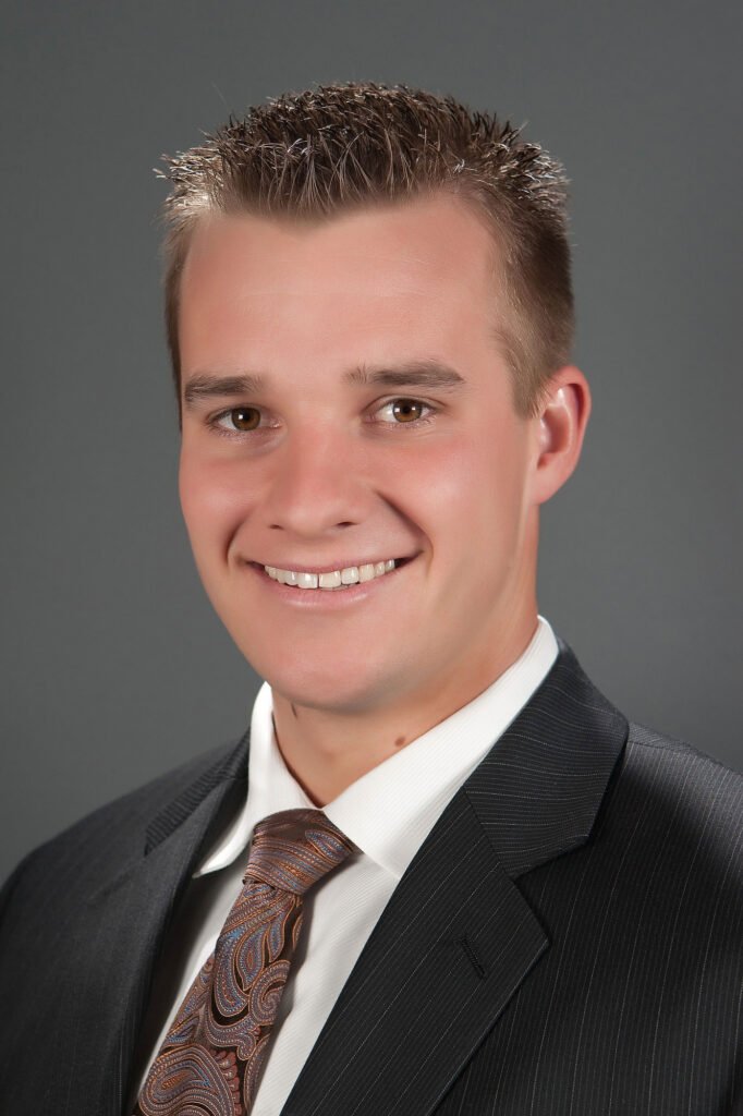 Man in a dark suit photographed against gray; portrait by Dave Cruz