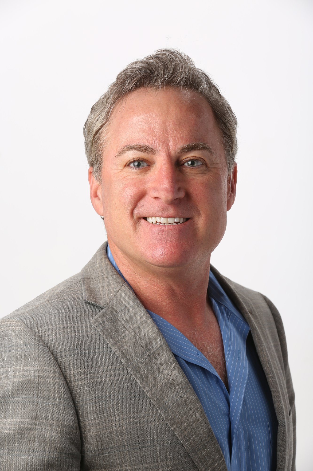 Man in a gray blazer photographed against white; portrait by Dave Cruz